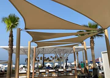 Sofitel Tamuda Bay — Réaménagement Beach F&B — Bar central, voiles d'ombrage et palmiers